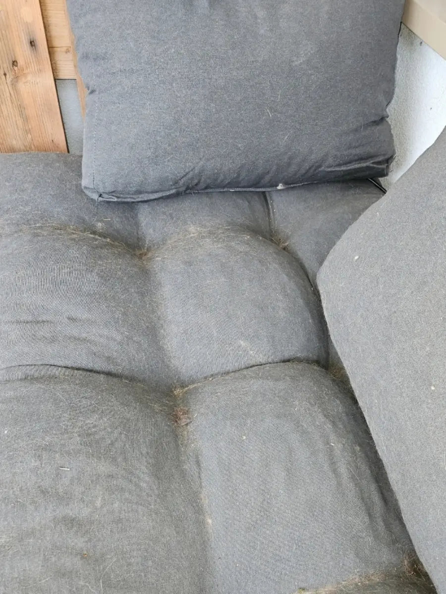 Graue Sofapolster voller Tierhaare vor der Reinigung mit dem Fellstopp Tierhaarentferner